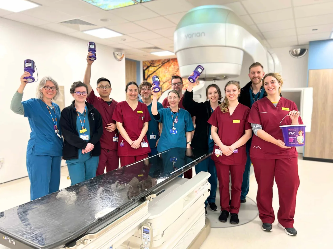 The radiotherapy team with charity collection pots in one of the linear accelerator treatment rooms at the RD&E