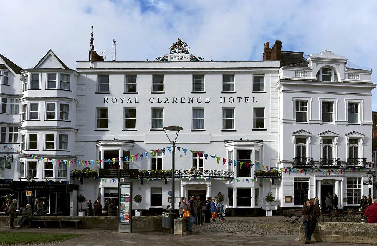 The white frontage of the Royal Clarence Hotel on Cathedral Yard, Exeter, with bunting across the ground floor and the hotel's crest on the roofline, before the 2016 fire.